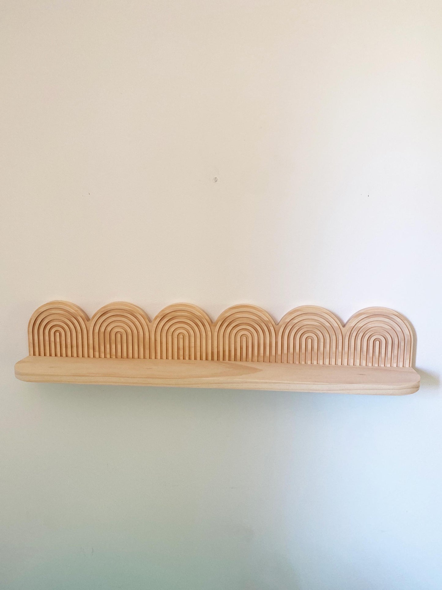Handcrafted wooden floating shelf with a decorative layered arch backplate, made from natural light wood. Mid-century modern and art deco-inspired design, perfect for wall-mounted storage and home decor. Ideal for displaying books, plants, or decorative accents in minimalist and contemporary spaces.