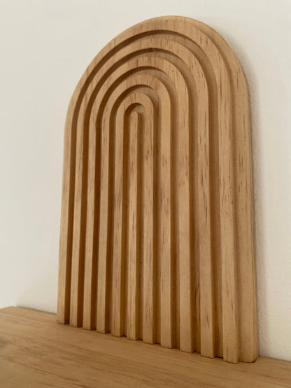 Close-up of a wooden wall-mounted shelf with an arched design, showcasing the intricate craftsmanship and natural wood finish.
